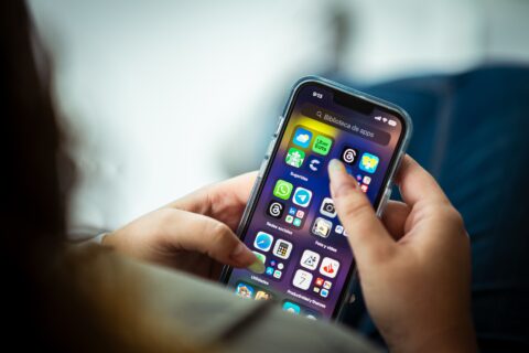 Bir kadın elindeki akıllı telefonda KADES uygulaması gibi güvenlik uygulamalarını inceliyor