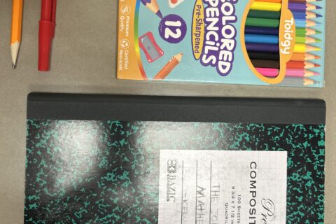 Okul çantası, defter, kalem ve kırtasiye malzemelerinden oluşan bir düzenleme